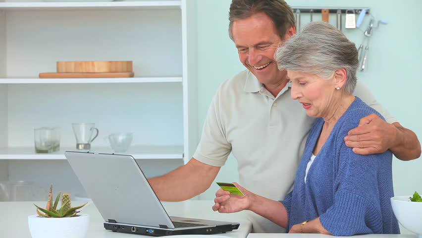Happy Middle Aged Couple Looking At Laptop And Talking In