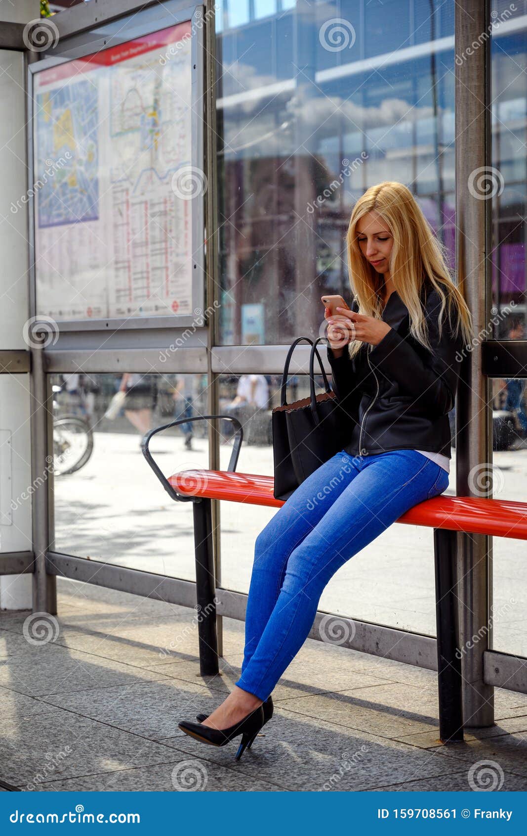 An Attractive Young Woman Waiting For The Bus At The Bus Stop Stock