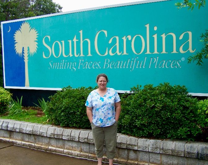A Woman Standing In Front Of A Sign For South Carolina