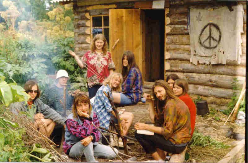 A Group Of People Sitting Next To Each Other In Front Of A Log Cabin